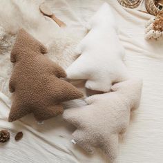 three pillows and two stuffed animals on a bed with white sheets, one has a brown christmas tree