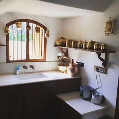 a kitchen area with sink, window and shelves