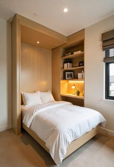 a bed with white sheets and pillows in a room next to a book shelf filled with books