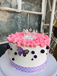 a white cake with pink flowers and a crown on top