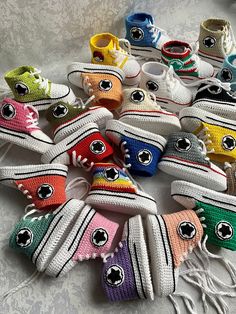 there are many pairs of baby shoes on the bed together, all in different colors and sizes