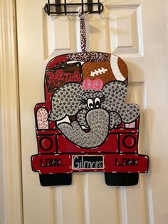 a door hanger with an elephant and footballs on it, hanging from the side of a white door