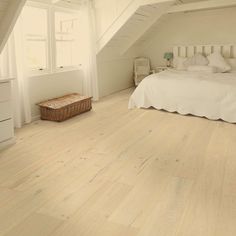 an attic bedroom with white walls and wood flooring on the ceiling, along with a bed