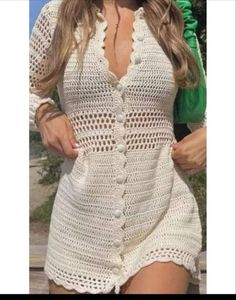 a woman is wearing a white crochet dress and black hat with her hands in her pockets