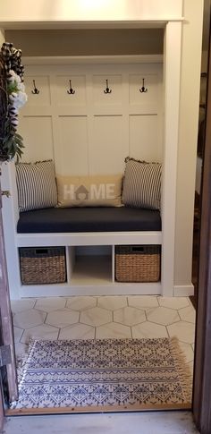 the entryway is decorated in white and has two benches with storage baskets on each side