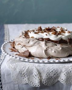 a cake with white frosting and chocolate shavings on a lace doily