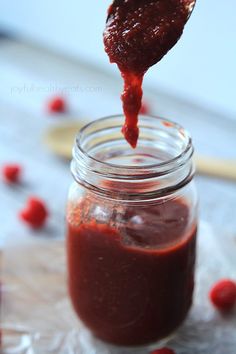 a spoon full of ketchup on top of a jar