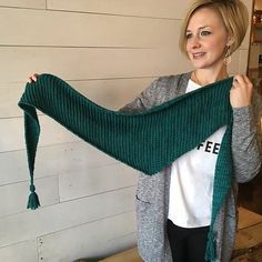 a woman is holding up a green scarf