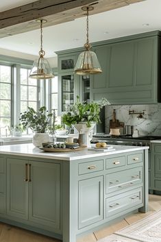 a large kitchen with green cabinets and marble counter tops, two hanging lights over the island