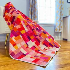 a colorful quilt on the floor next to a chair