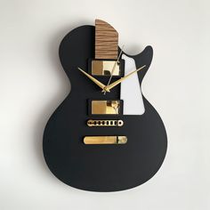 a black guitar shaped clock with gold accents