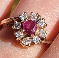 This lovely genuine ruby ring is surrounded by beautiful diamonds. The central ruby is approximately .40ctw. The diamonds are G color, VS clarity and are a total of. 42ctw. Set in a beautiful filigree setting. A sizable 5.75-6 set in Yellow Gold. A perfect gift for any girl! Thank you kindly. Classic Cluster Ruby Ring, Ruby Ring With Diamond Cluster And Brilliant Cut, Cluster Ruby Ring With Brilliant Cut Diamonds, Cluster Ruby Ring With Diamonds, Cluster Ruby Diamond Ring With Center Stone, Cluster Ruby Ring With Center Stone, Red Diamond Cluster Ring With Halo Setting, Dazzling Ruby Ring With Vvs Clarity, Red Diamond Cluster Ring With Vvs Clarity