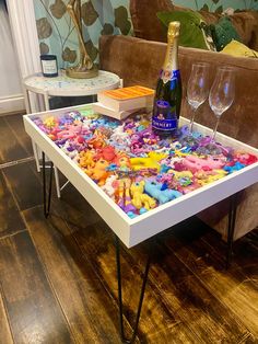 a table that has some wine glasses and stuffed animals on it in front of a couch