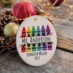 a personalized ornament with crayons and pine cones on a wooden table