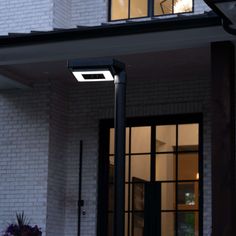 a street light sitting in front of a white brick building with windows on each side