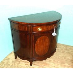 an old fashioned wooden cabinet with two doors and knobs on the front, against a blue wall