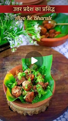 a bowl filled with food sitting on top of a wooden table next to potted plants