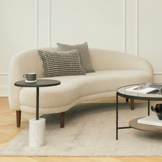 a white couch sitting on top of a wooden floor next to a table and chair