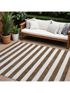 a brown and white striped rug sitting on top of a wooden bench next to potted plants