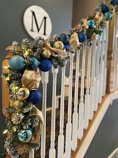 christmas decorations on the banisters of a house with blue and gold baubies