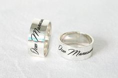 two silver rings with names on them sitting next to each other in front of a white background