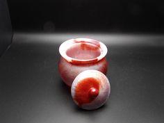 two red and white vases sitting on top of a black table next to each other