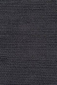 a black rug with braiding on the top and bottom, it is very dark