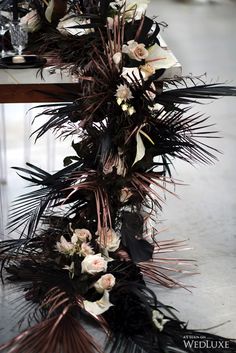 the table is decorated with black and white flowers, feathers and candles for an elegant touch