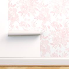 an empty roll of toilet paper next to a wall with pink flowers on the wall