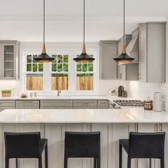 three black chairs are sitting at the bar in this modern kitchen with white countertops and gray cabinets