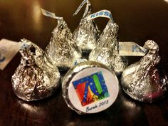 some silver foiled candies are sitting on a table with ribbons around them,