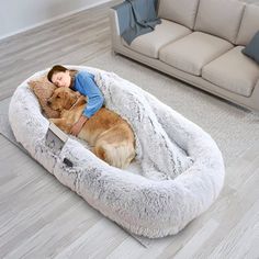 a person laying on top of a dog bed with a large brown dog in it