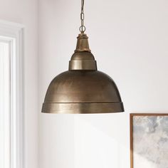 an antique brass pendant light hanging from a white wall in a living room or dining room