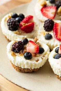 small desserts are arranged on a plate with berries and nuts in the top half