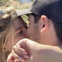 a man and woman kissing each other in front of water