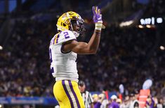 a football player with his hand up in the air and wearing a uniform that says lsu