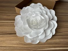 a white flower sitting in a box on top of a wooden table