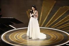 a woman in a white dress on stage with an award for best female vocal performance