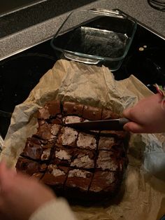 someone is cutting into some brownies on top of the oven sheeted in wax paper