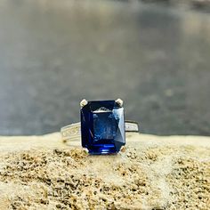 A beautiful lab created blue sapphire in an emerald cut weighing 5.62cts. set in a platinum ring and channel set with round brilliant cut diamonds weighing approximately .52cts. with clarity and color approximately SI1, G.  This ring has 18kt. yellow gold scroll detail design on the sides of ring.  A high polish finish weighing 8.01 grams.  This ring measurers in width across the top at 12.0mm tapering in the back to 2.32mm.  Size 5 We can size to fit your finger. Detail Design, Lab Created Emerald, Valley View, Platinum Ring, Channel Set, Creative Jewelry, Round Brilliant Cut Diamond, Brilliant Cut Diamond, Emerald Cut