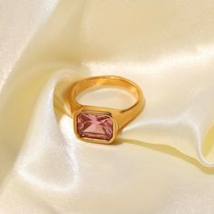 Introducing the Forza Gold Pink Gemstone Signet Ring, a dazzling fusion of elegance and modern style. Crafted from high-quality stainless steel with a luxurious 18 karat gold finish, this ring exudes sophistication. The on-trend square-ish design, paired with a sparkling array of gemstone options including black, clear, pink, and green zircons, adds a touch of glamour to any ensemble. Whether you're looking for a statement piece or a stylish gift, the Forza Gold Gemstone Signet Ring is a radiant Modern Gold Crystal Ring With Gemstone, Modern Gold Crystal Ring For Gift, Modern Gold Crystal Ring Gift, Modern Gold Square Signet Ring, Modern Square Gold Rings, Elegant Gold Square Signet Ring, Elegant Gold Square Cut Ring, Modern Gold Signet Ring With Rectangular Stone, Gold Rectangular Crystal Ring