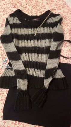 a black and white striped sweater sitting on top of a bed next to a pillow