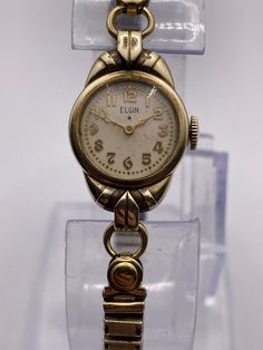 a gold watch sitting on top of a clear display case