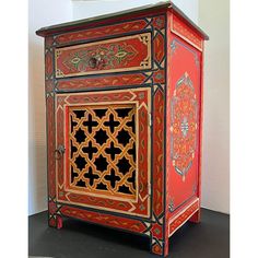 an ornately painted cabinet is shown in red and gold colors, with intricate designs on the doors