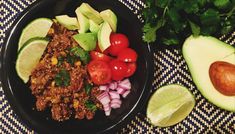 a black plate topped with meat and veggies next to an avocado