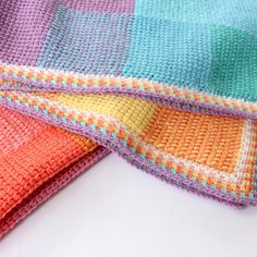 three crocheted blankets folded on top of each other in different colors and patterns