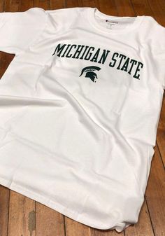 Champion Michigan State Spartans White Arch Mascot Short Sleeve T Shirt - 14752610 Game Day Cotton T-shirt With Screen Print, White Game Day Fan Apparel T-shirt, White Fan Apparel T-shirt For Game Day, Collegiate Team-colored T-shirt With Screen Print, Team Spirit Cotton T-shirt With Team Logo, Collegiate T-shirt With Team Colors And Screen Print, White Collegiate Screen Print Top, Team Logo Cotton T-shirt For Team Spirit, Sports Fan Cotton T-shirt With Team Name