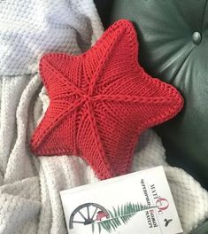 a red knitted star ornament sitting on top of a green leather chair