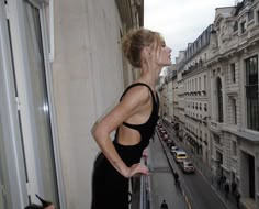 a woman standing on a balcony looking out at the street