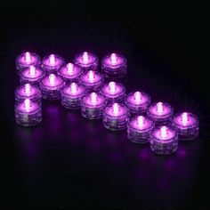 purple tealight candles are arranged in the shape of an arrow on a black background